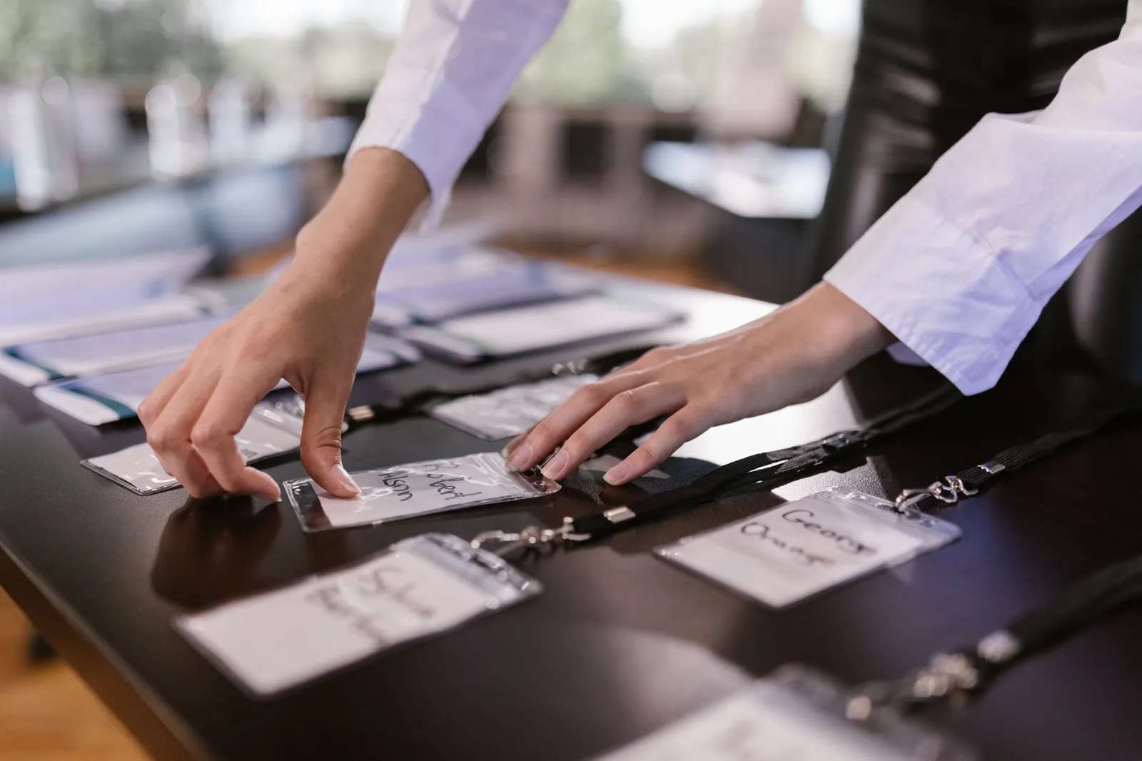 Close-up of hands arranging name tags on a conference table, preparing for a corporate event. Stock photo for the ALFA News guide: Corporate Event Alerts: A Guide for Indian Investors.