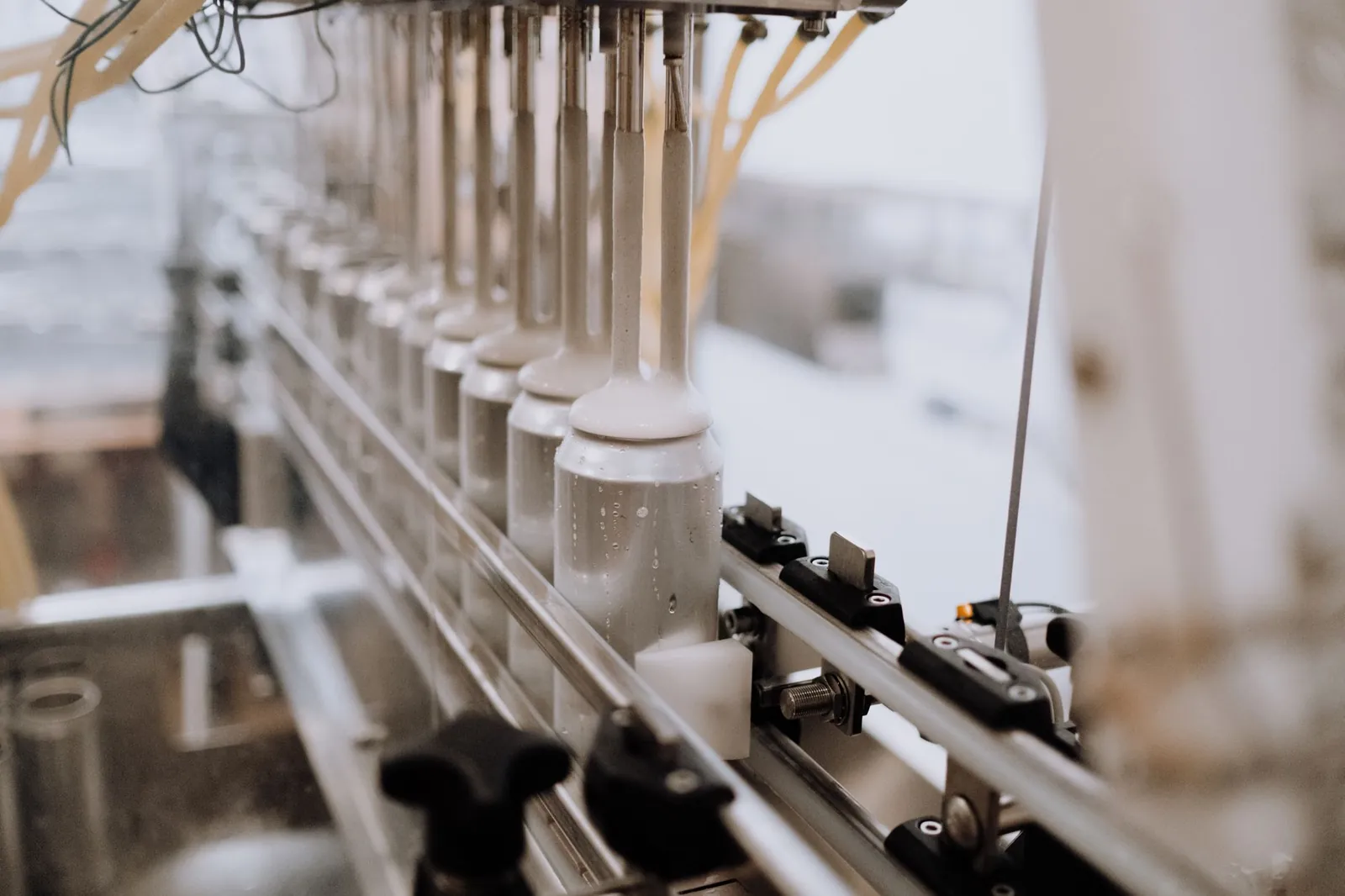 Close-up of automated canning equipment in a brewery, highlighting the manufacturing process. Stock photo illustrating Raghav Productivity Enhancers' regulatory approval story.