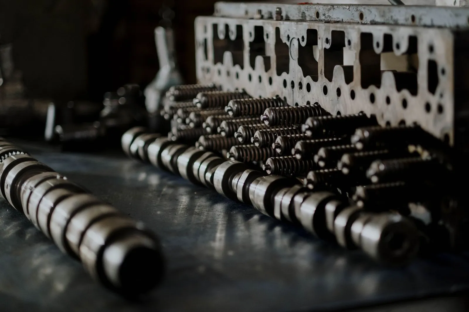 Detailed close-up of engine components including camshafts and springs on a workbench. Stock photo illustrating OBSC Perfection's fund raise story.