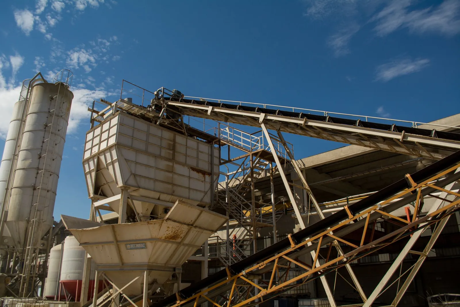 View of rusty machinery and structures at an industrial plant in Córdoba under a clear blue sky. Stock photo illustrating Dalmia Bharat's production started story.