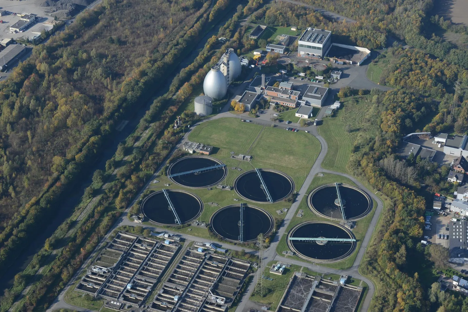 Aerial photograph of a wastewater treatment plant surrounded by autumn trees, showcasing ecological and industrial elements. Stock photo illustrating Enviro Infra Engineers' new order story.