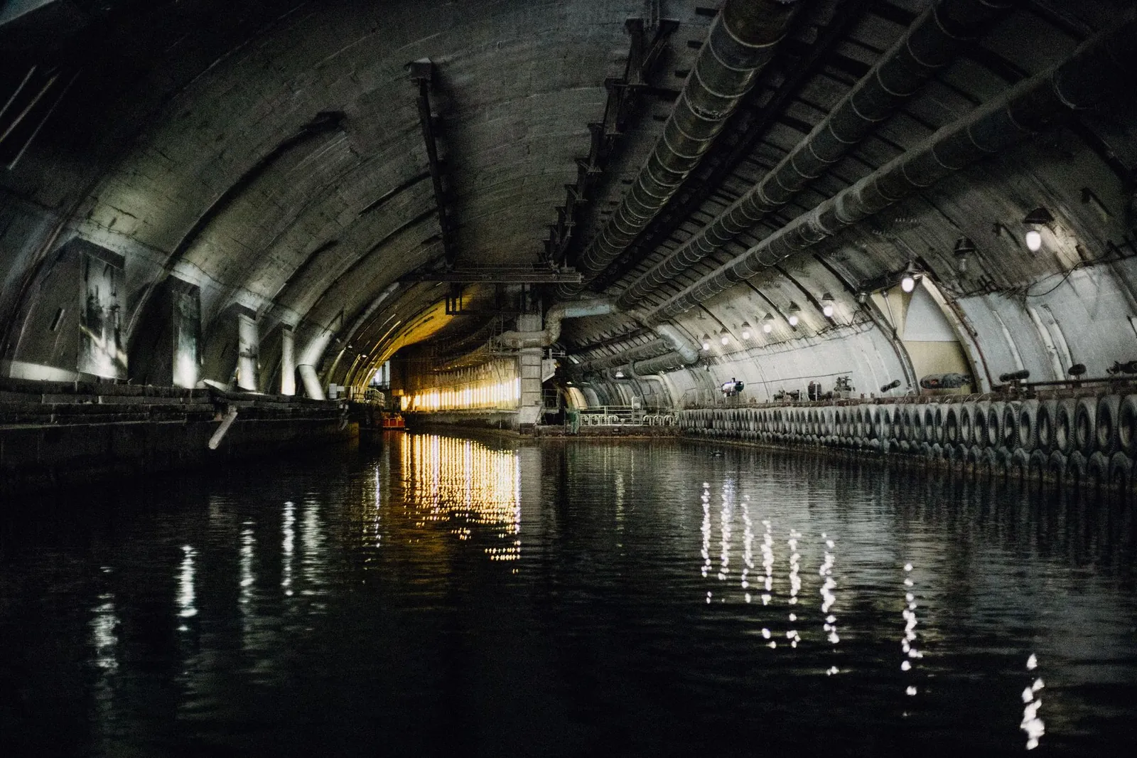Dark and atmospheric underground canal tunnel with water reflections and industrial architecture. Stock photo illustrating Afcons Infrastructure's new order story.