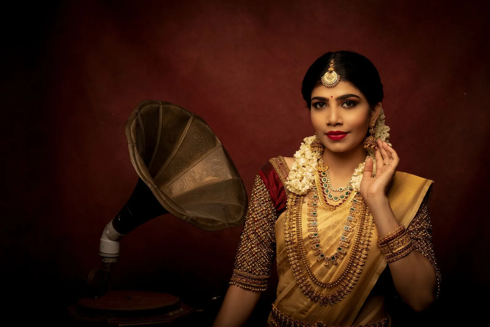 Indian bride in traditional attire with gold jewelry, posing beside a vintage phonograph. Stock photo illustrating PC Jeweller's fund raise story.