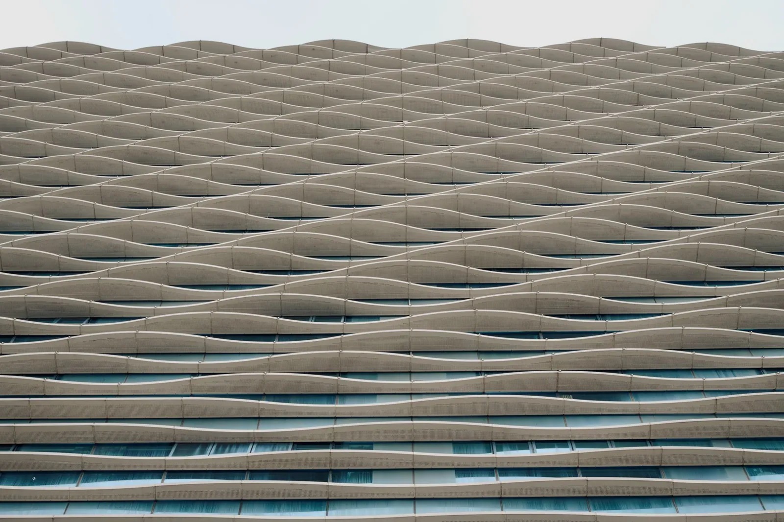 A stunning architectural facade featuring a wavy, geometric design in urban setting. Stock photo illustrating HRS Aluglaze's new order story.
