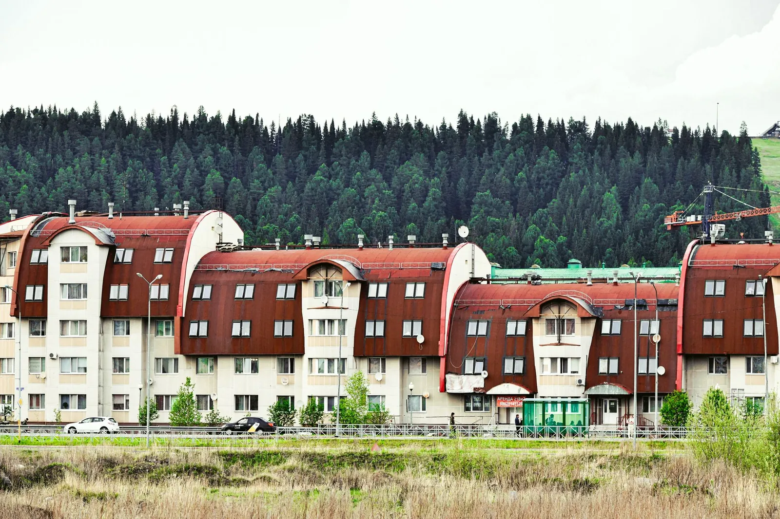 Contemporary apartment complex with unique architecture set against a lush forest backdrop. Stock photo illustrating Laxmi Goldorna House's expansion story.