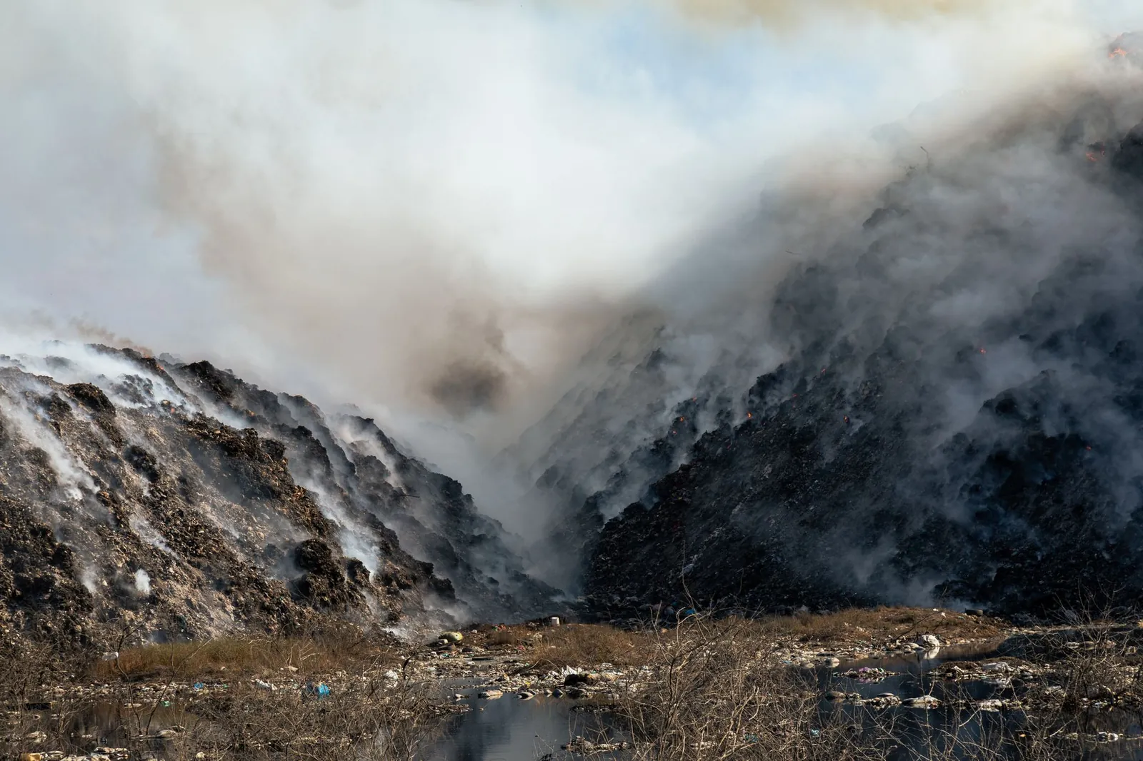 Thick smoke billows from a burning landfill surrounded by piles of waste and trash. Stock photo illustrating Felix Industries' new order story.