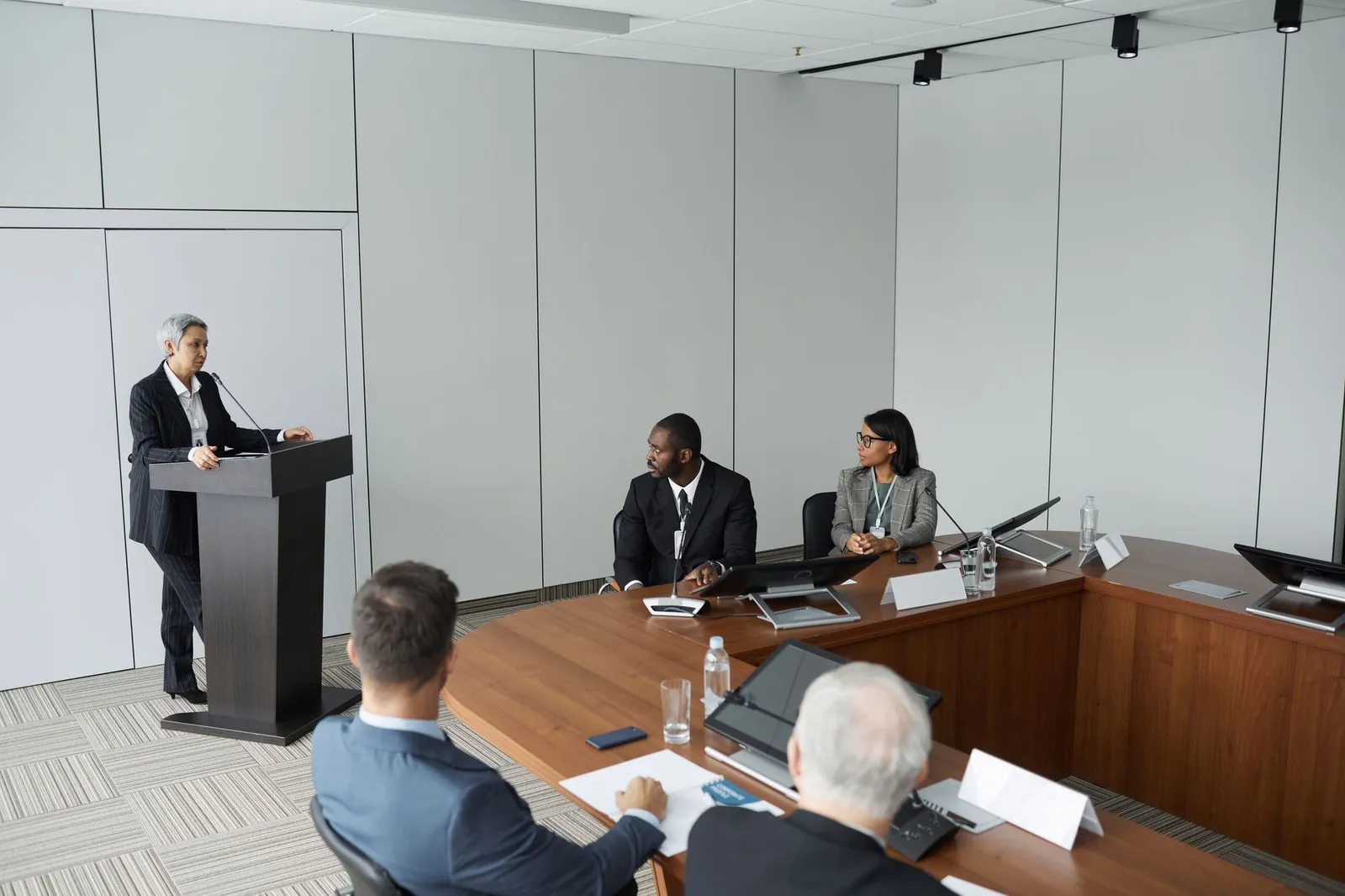 Diverse group of professionals in a formal meeting setting with a speaker at the podium. Stock photo illustrating EMA Partners India's partnership story.