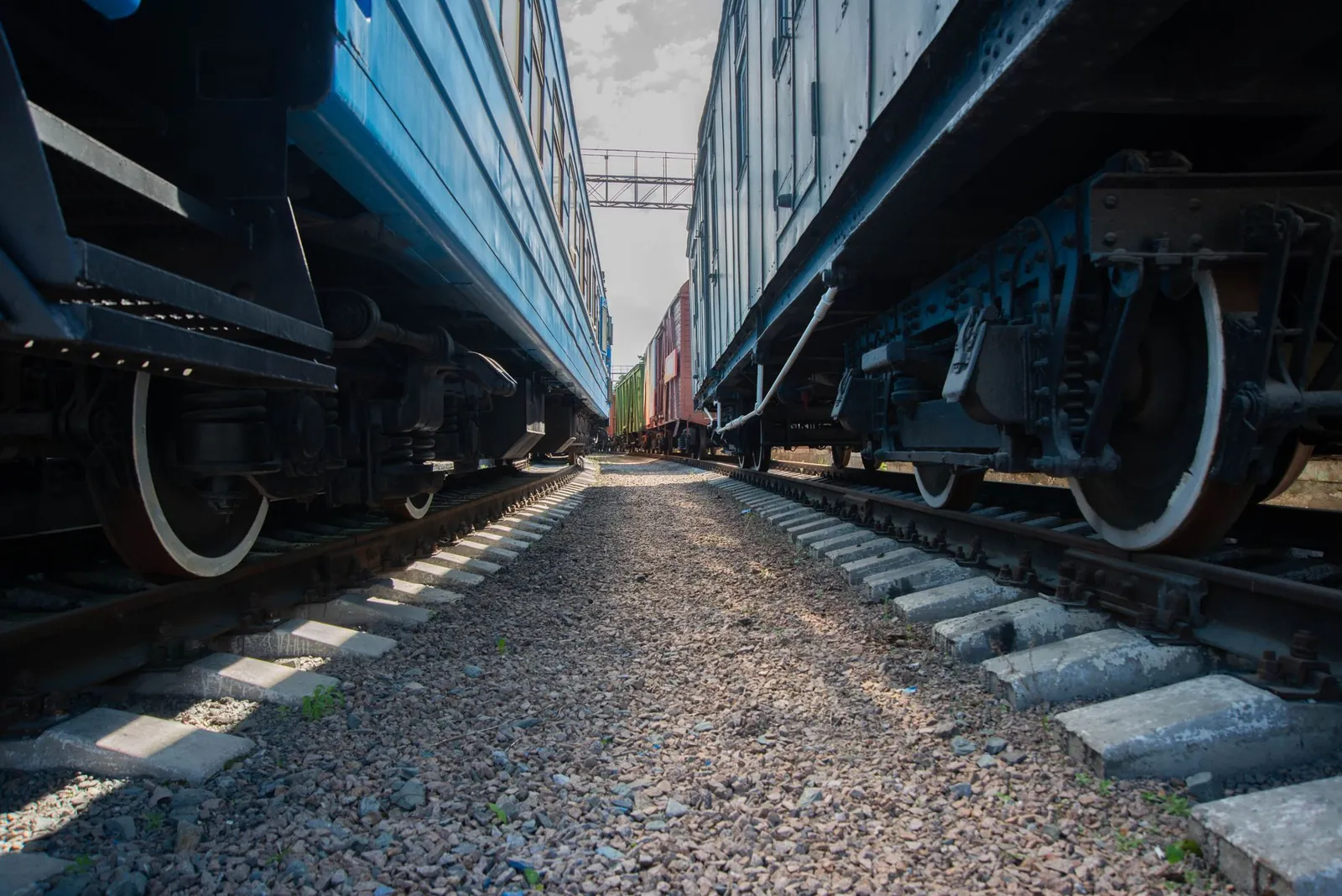 Detailed view between two railway cars on parallel tracks with a gritty texture. Stock photo illustrating Oriental Rail Infrastructure's expansion story.
