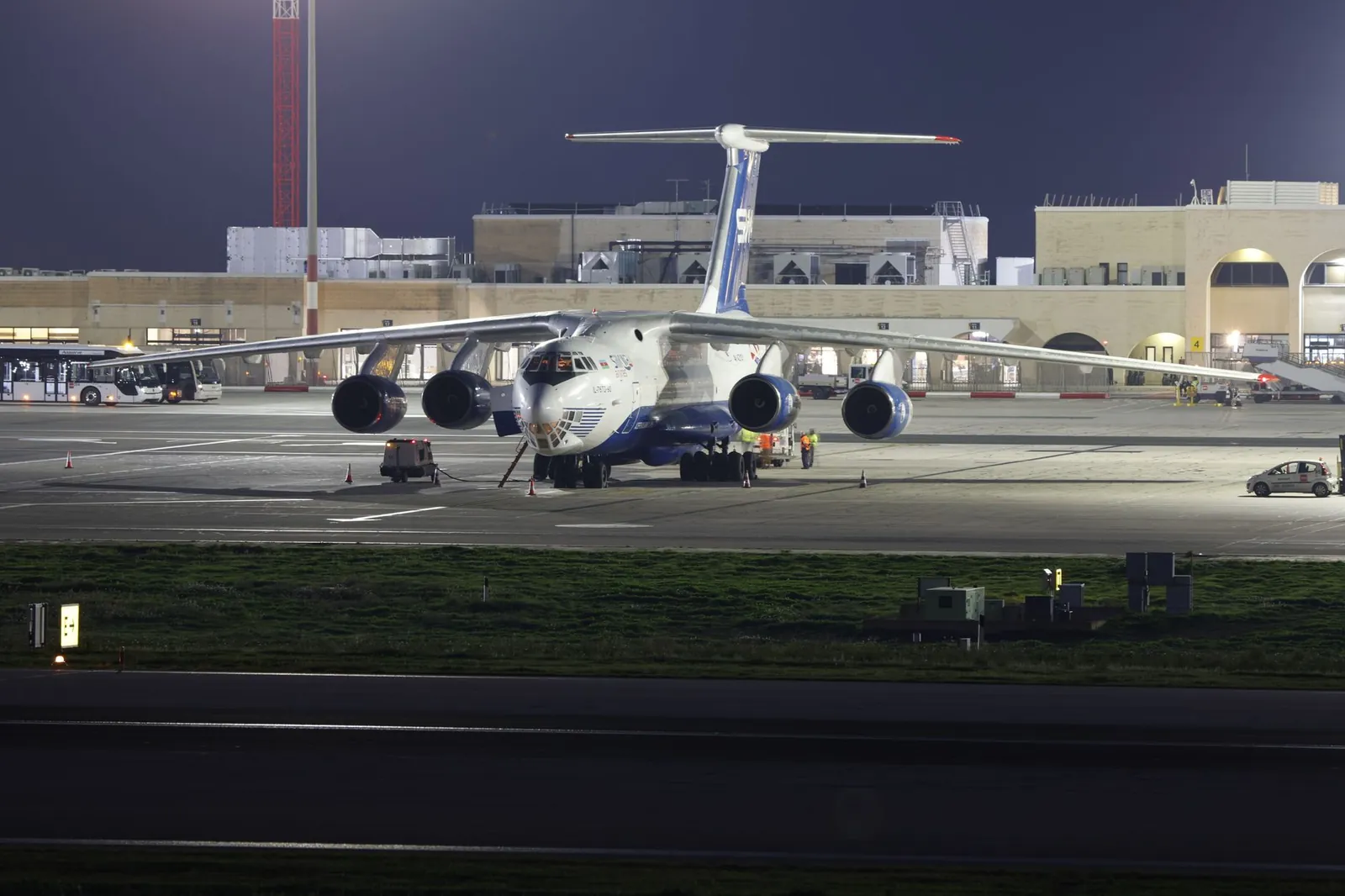 A large cargo aircraft parked on an airport runway at night, under bright lights. Stock photo illustrating Afcom Holdings' partnership story.