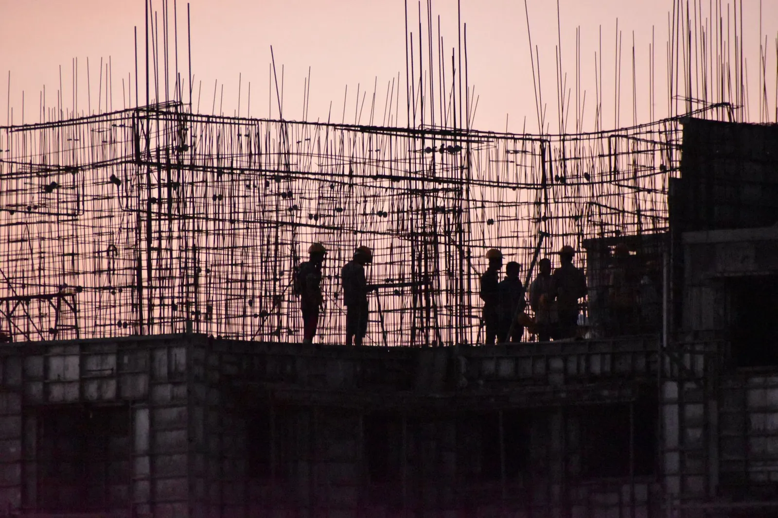Silhouettes of workers at a construction site in India during sunset. Stock photo illustrating SRM Contractors' fund raise story.