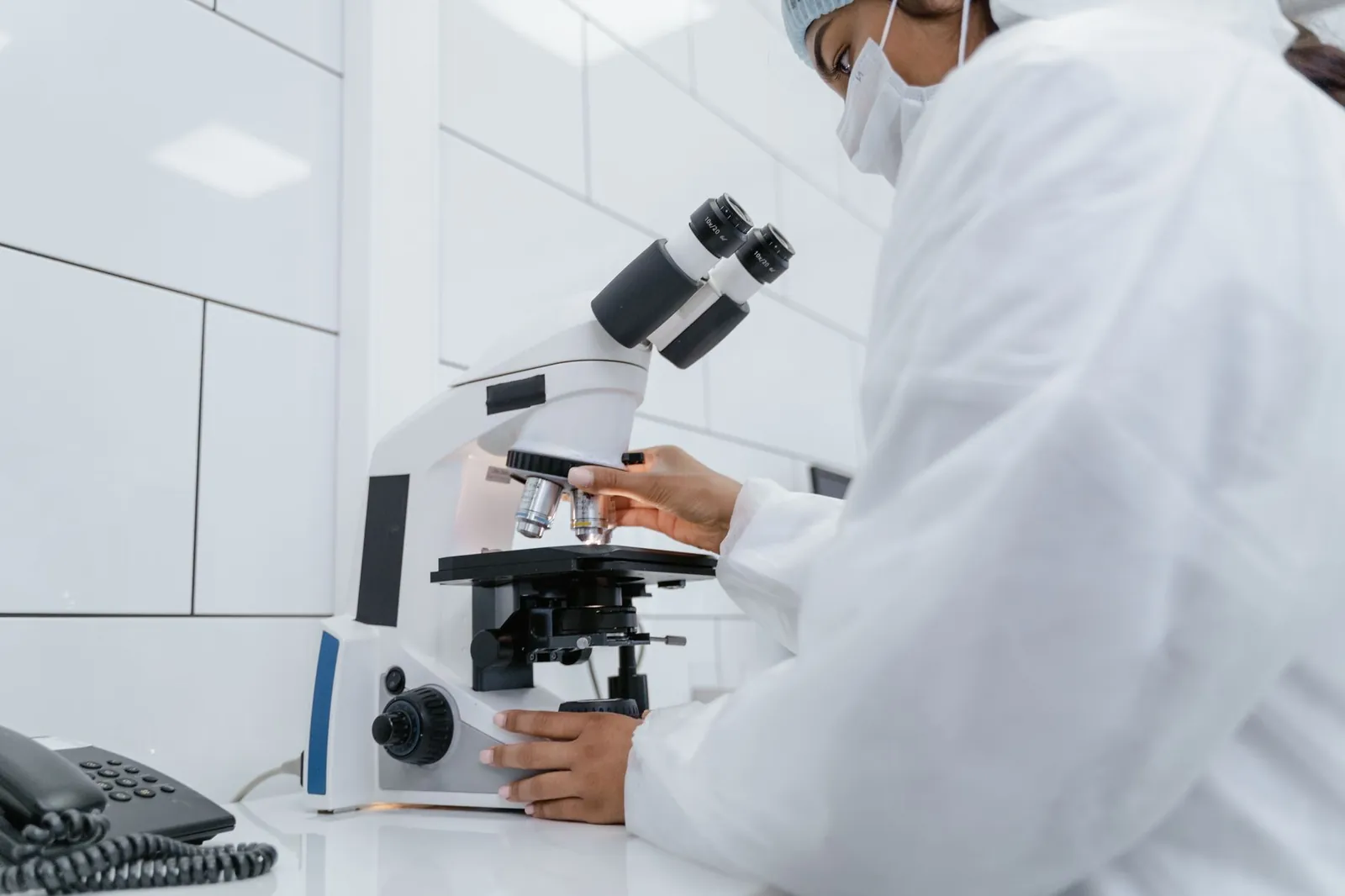 Scientist using microscope for research in a modern laboratory setting. Stock photo illustrating Anlon Healthcare's earning call story.