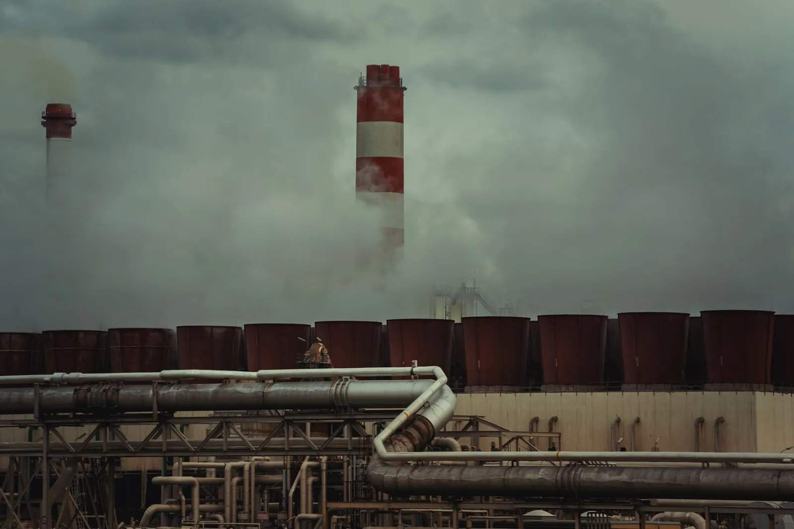 An industrial factory with chimneys releasing smoke under a cloudy sky, conveying urban pollution. Stock photo illustrating DEE Development Engineers' new order story.