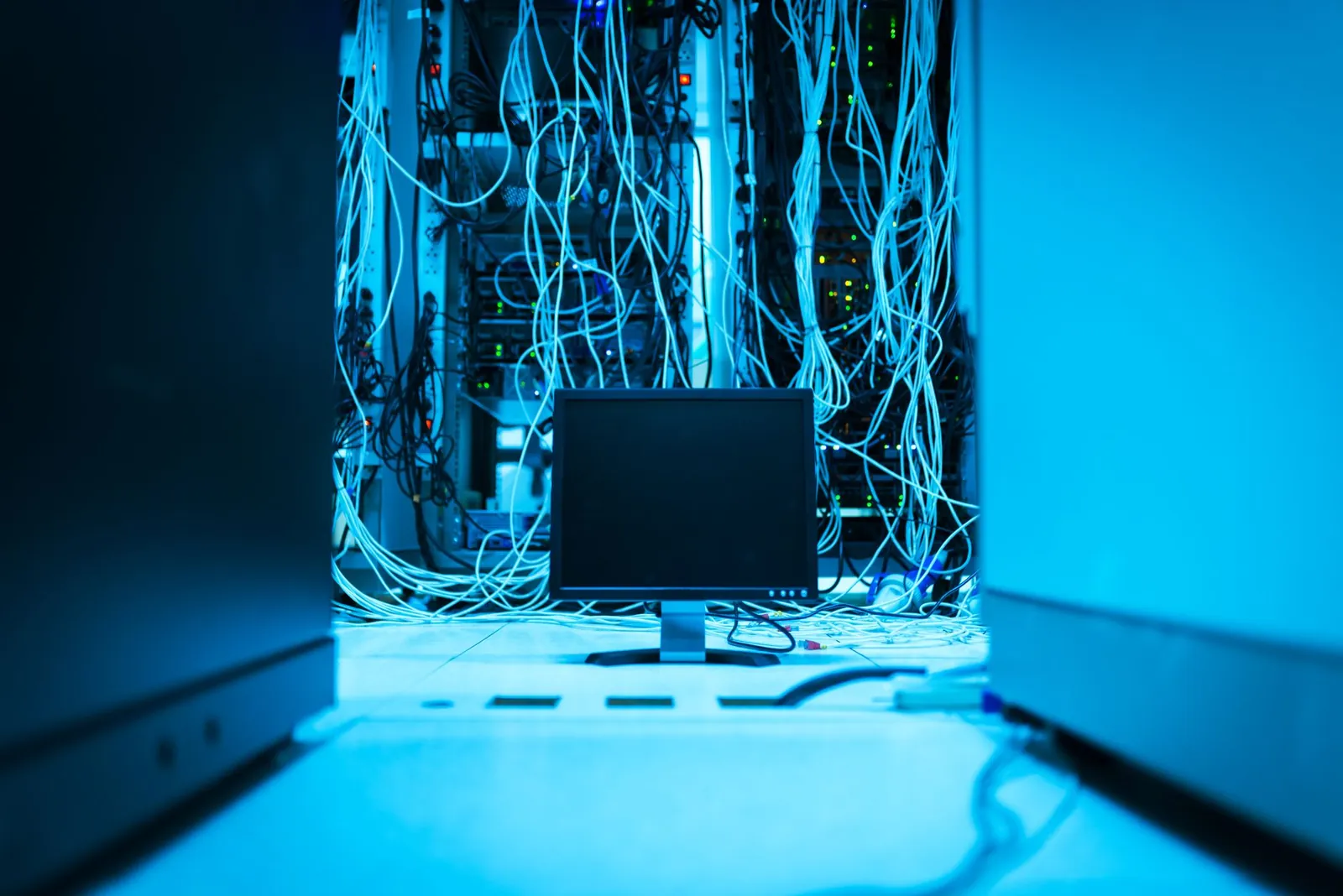 A complex network of cables in a data center with a monitor in the foreground. Stock photo illustrating String Metaverse's earning call story.