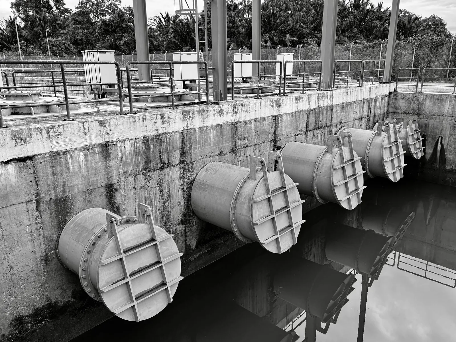 Monochrome image of large industrial water pipes with valves. Stock photo illustrating Indian Hume Pipe Company's new order story.