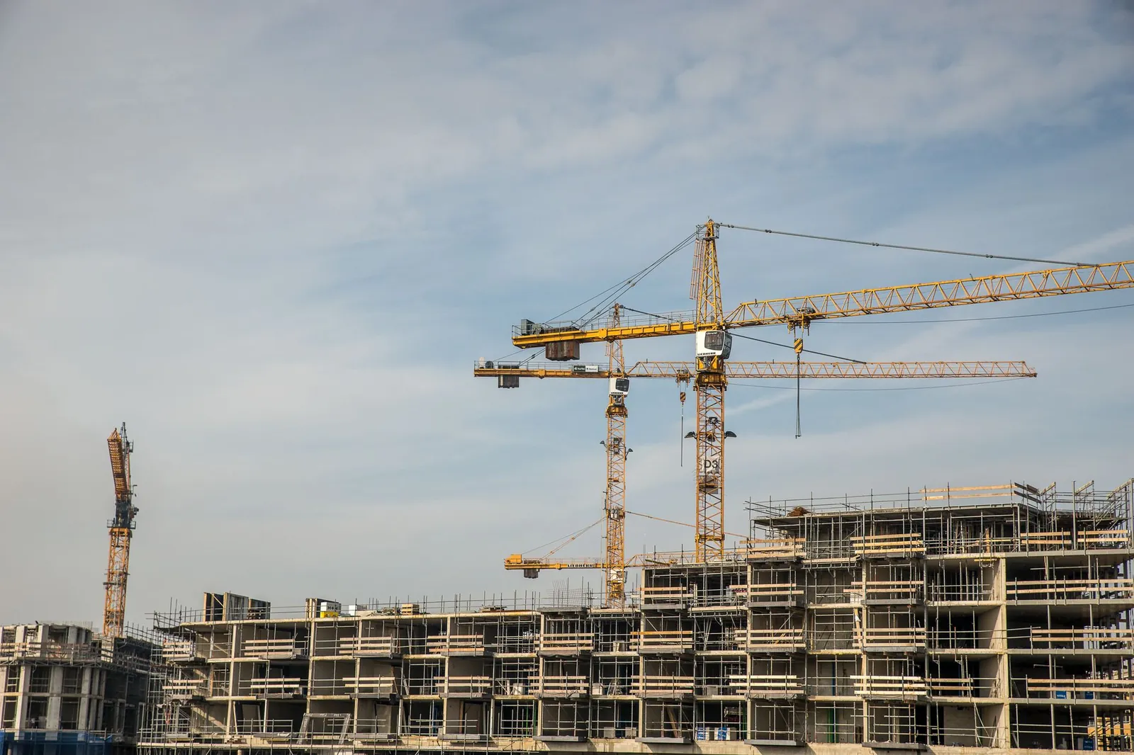 Modern construction site with cranes against blue sky, showcasing urban development. Stock photo illustrating Embassy Developments' fund raise story.