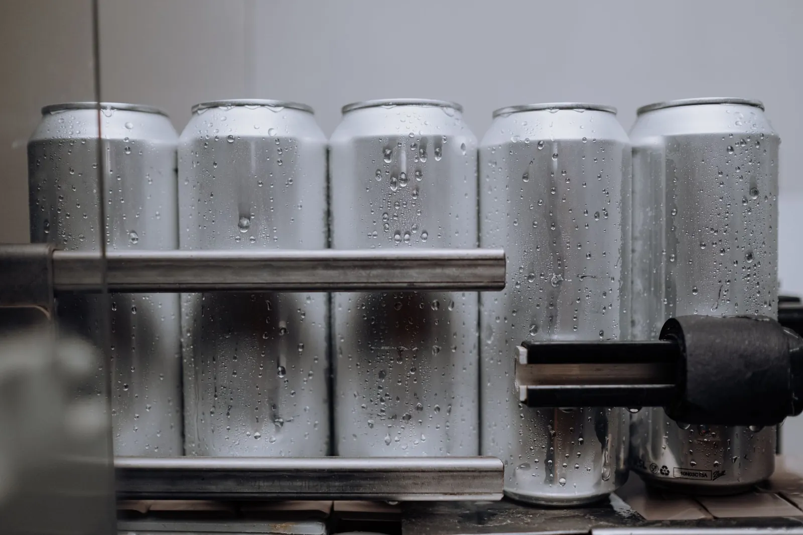 Close-up of condensation-covered aluminum cans on a production line, highlighting cool refreshment. Stock photo illustrating GSM Foils' earning call story.