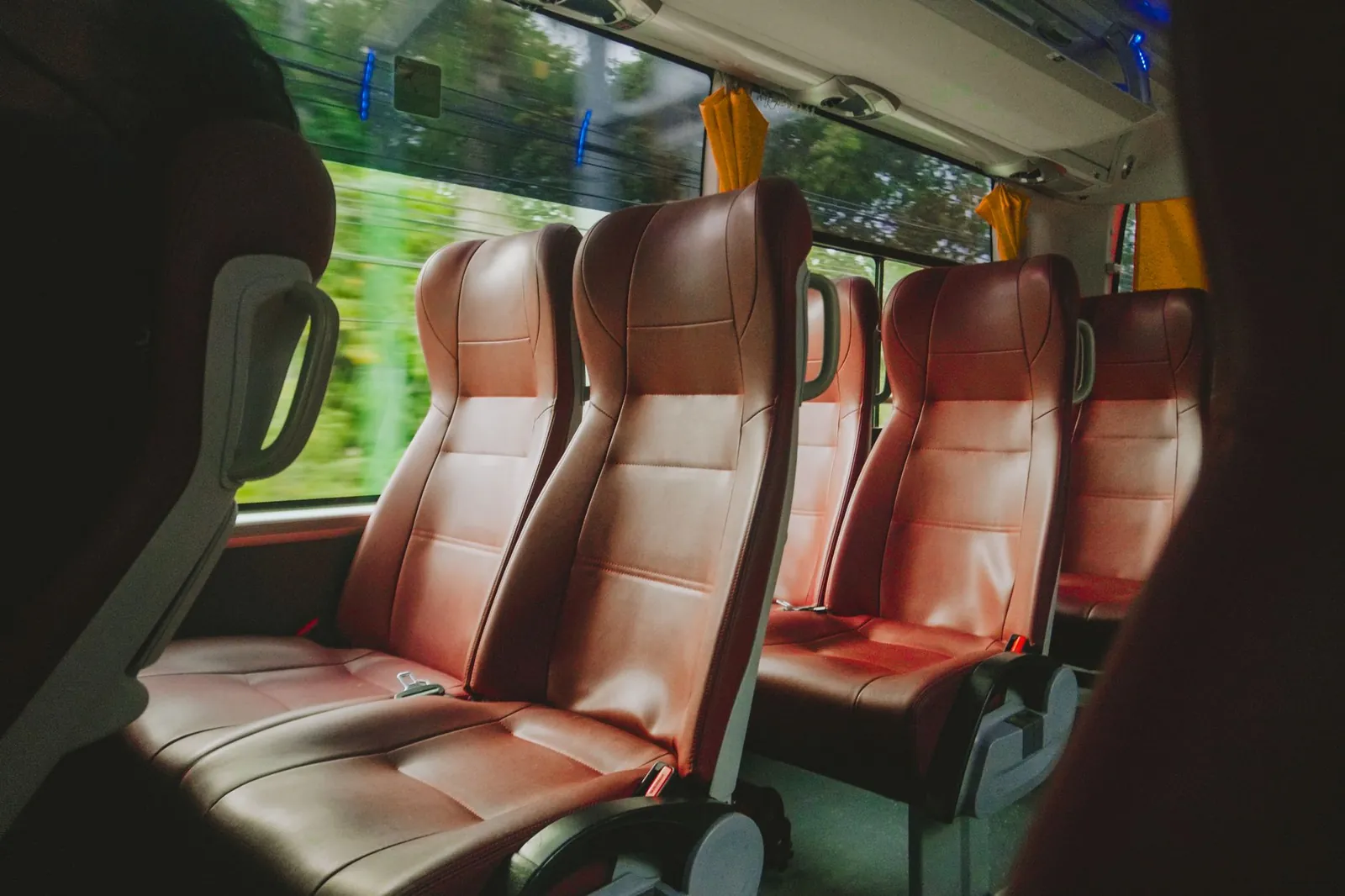 Interior view of a luxurious bus with empty red leather seats, offering comfort and style. Stock photo illustrating JBM Auto's product launched story.