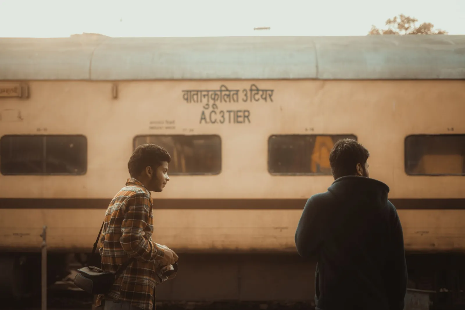 Commuters at Jammu railway station stand beside an AC 3-tier train. Stock photo illustrating Dhara Rail Projects' new order story.