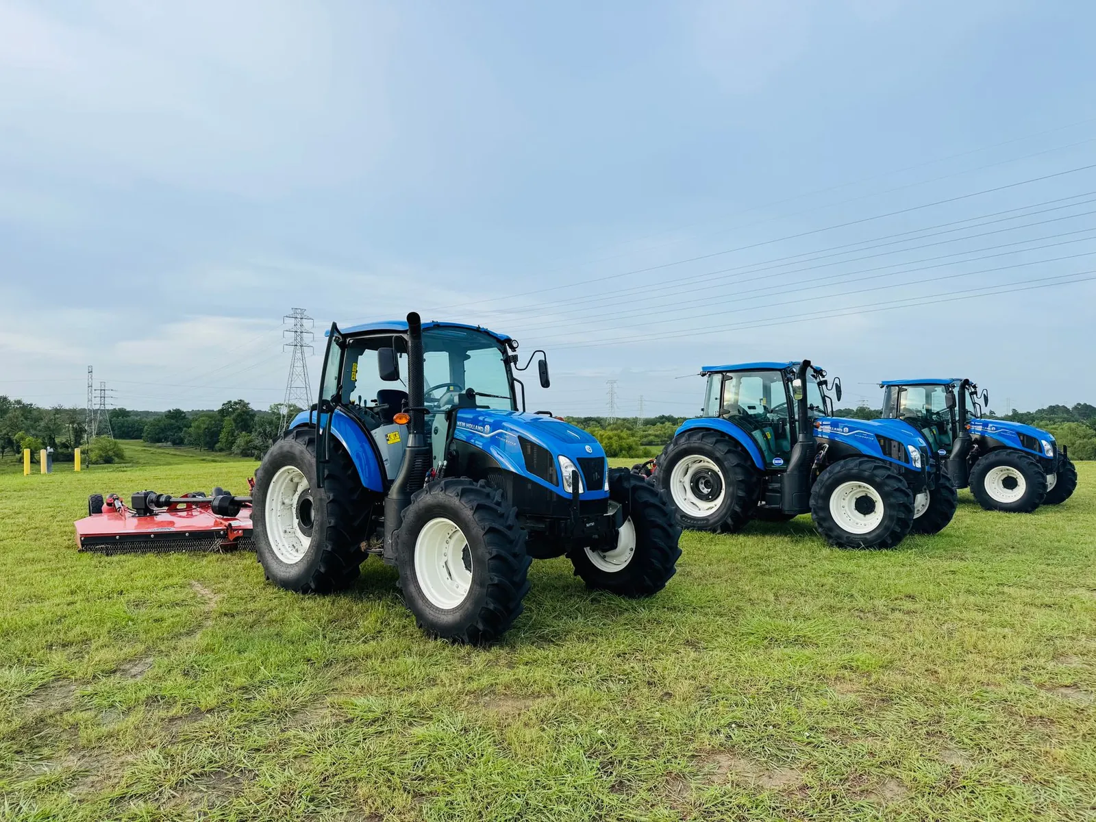 Three blue tractors parked in a Houston field against a clear sky, showcasing agricultural machinery. Stock photo illustrating Carraro India's earning call story.