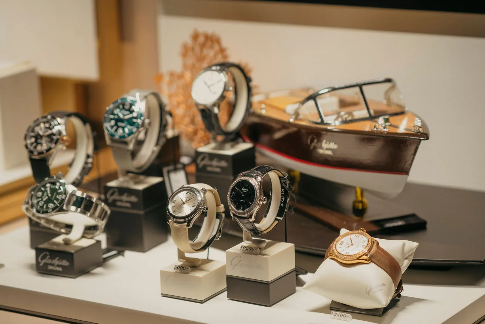 A collection of luxury watches elegantly displayed beside a model boat in a retail environment. Stock photo illustrating Ethos' expansion story.