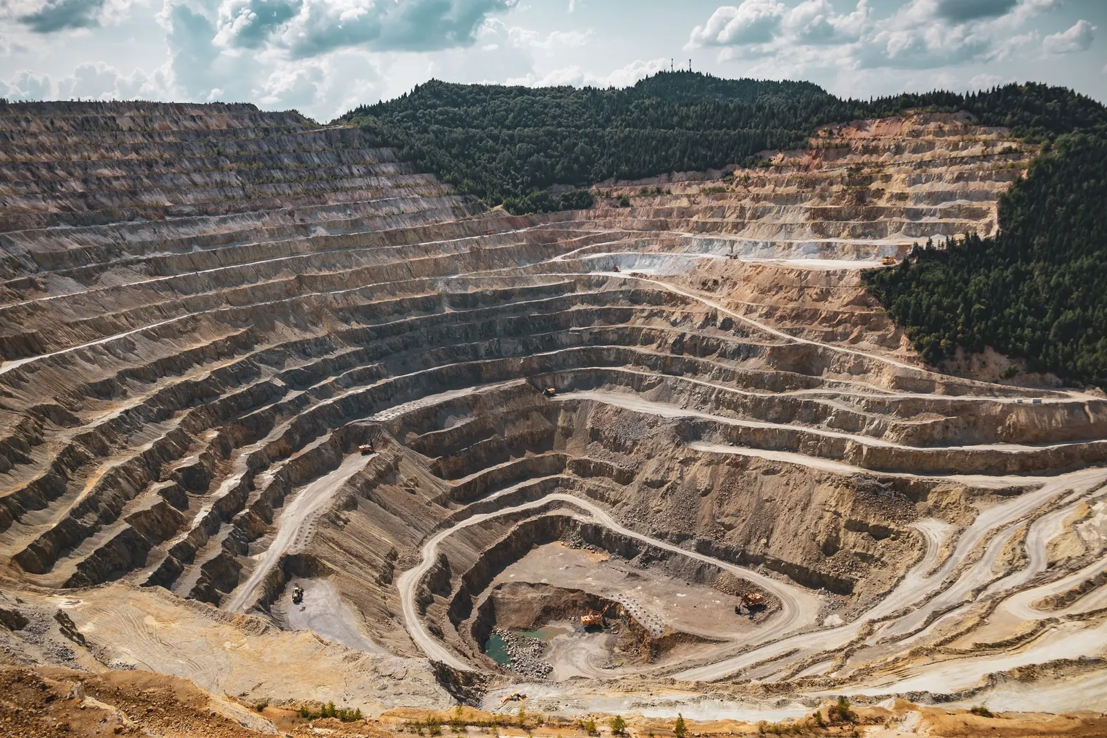 Aerial view of a large open-pit mine with terraced excavation during summer. Stock photo illustrating Ganesh Infraworld's new order story.