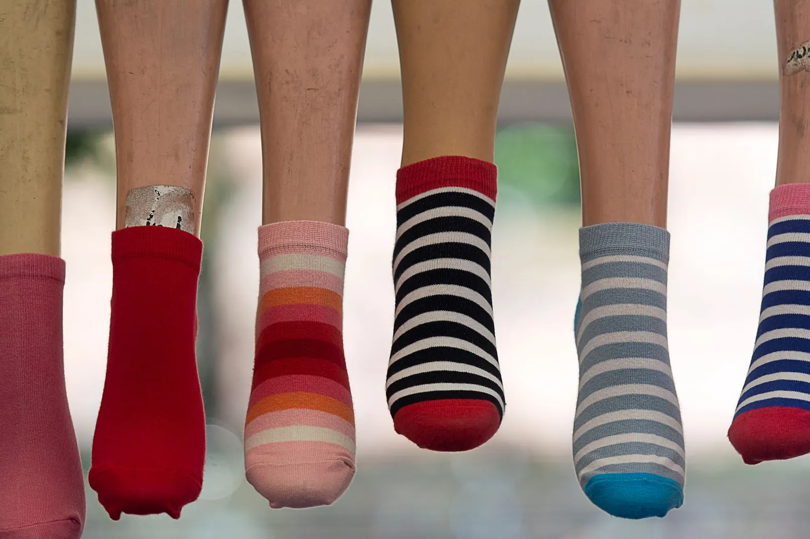 A vibrant array of striped socks displayed on mannequin legs, showcasing fashion variety. Stock photo illustrating Virat Industries' earning call story.