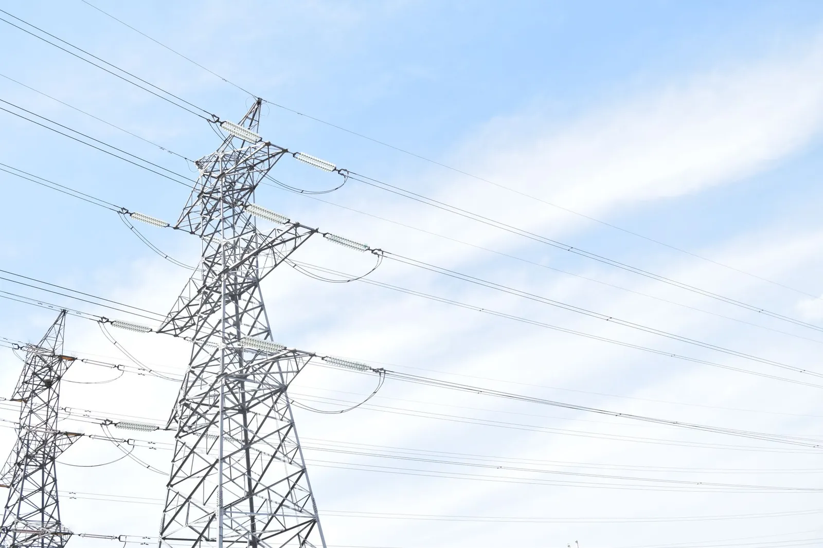 Steel transmission towers against blue sky, highlighting energy and electricity infrastructure. Stock photo illustrating Power Grid Corporation of India's fund raise story.
