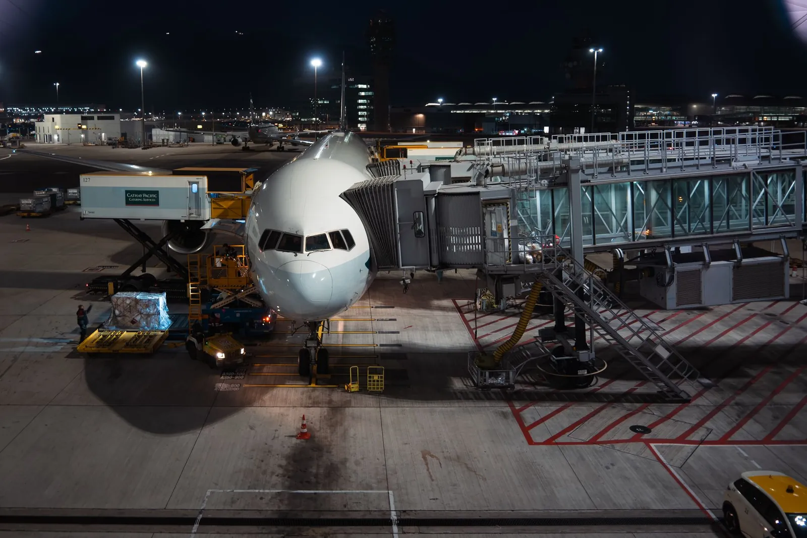 Airplane parked at airport gate during nighttime, unloading cargo and passengers. Stock photo illustrating Afcom Holdings' fund raise story.