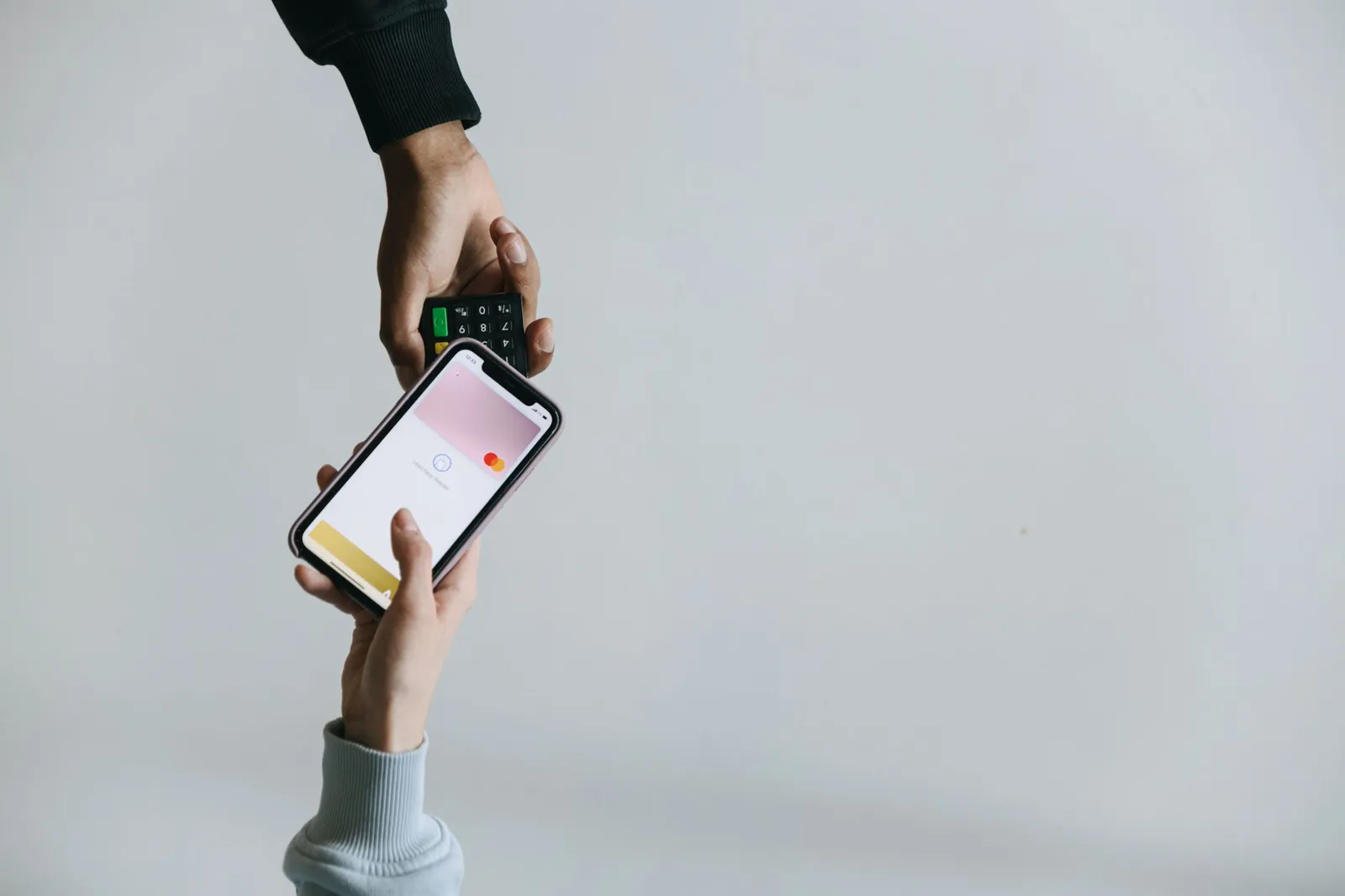 Hands using smartphone and terminal for cashless payment, showcasing modern transaction methods. Stock photo illustrating IndusInd Bank's partnership story.