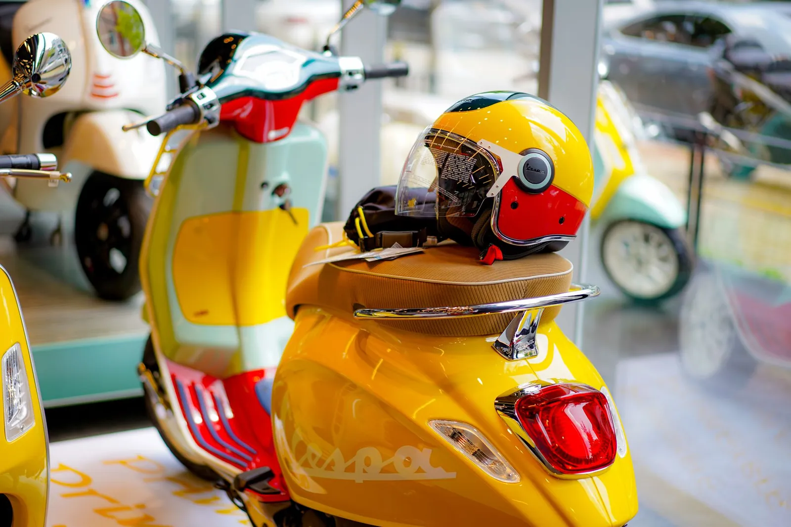 Bright yellow Vespa scooter with a stylish helmet displayed in a showroom, showcasing vibrant colors and retro design. Stock photo illustrating Mercury Ev-Tech's expansion story.