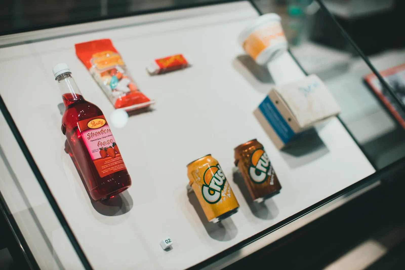 Collection of drinks and snacks showcased in a glass display case, indoors. Stock photo illustrating AWL Agri Business' product launched story.