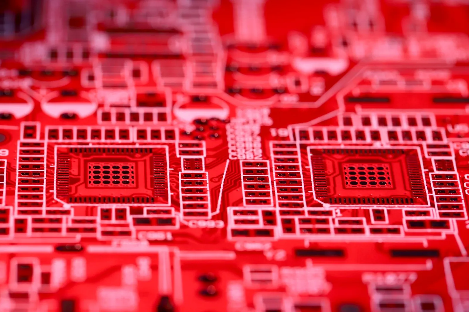 Modern bright printed board with electric circuits of contemporary technical device with red surface placed on blurred background in room. Stock photo illustrating Apollo Micro Systems' new order story.
