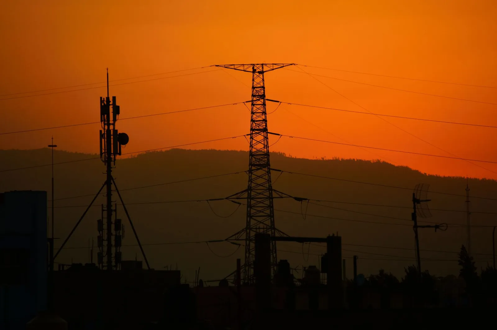 Power lines silhouetted against an orange sunset sky, conveying energy and tranquility. Stock photo illustrating Valiant Communications' new order story.