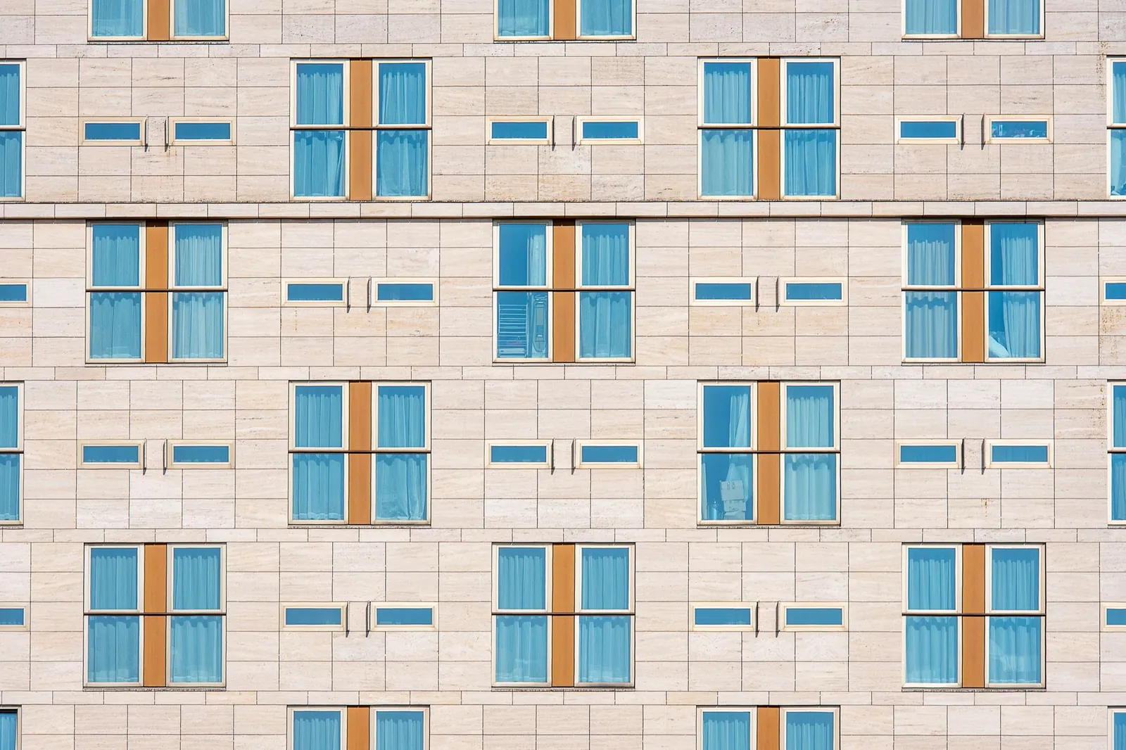 Modern hotel facade showcasing symmetrical design with blue windows and beige stone. Stock photo illustrating Embassy Office Parks REIT's product launched story.