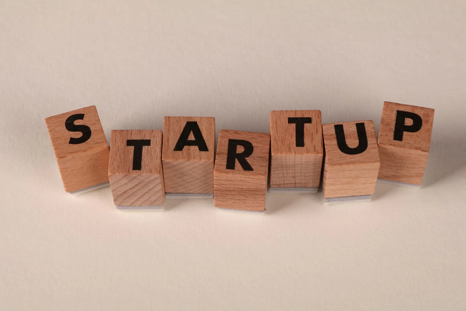 Wooden blocks forming the word 'STARTUP' on a neutral background, symbolizing new business ventures. Stock photo for the ALFA News guide: Joint Venture Announcements: SEBI Rules and Risks.
