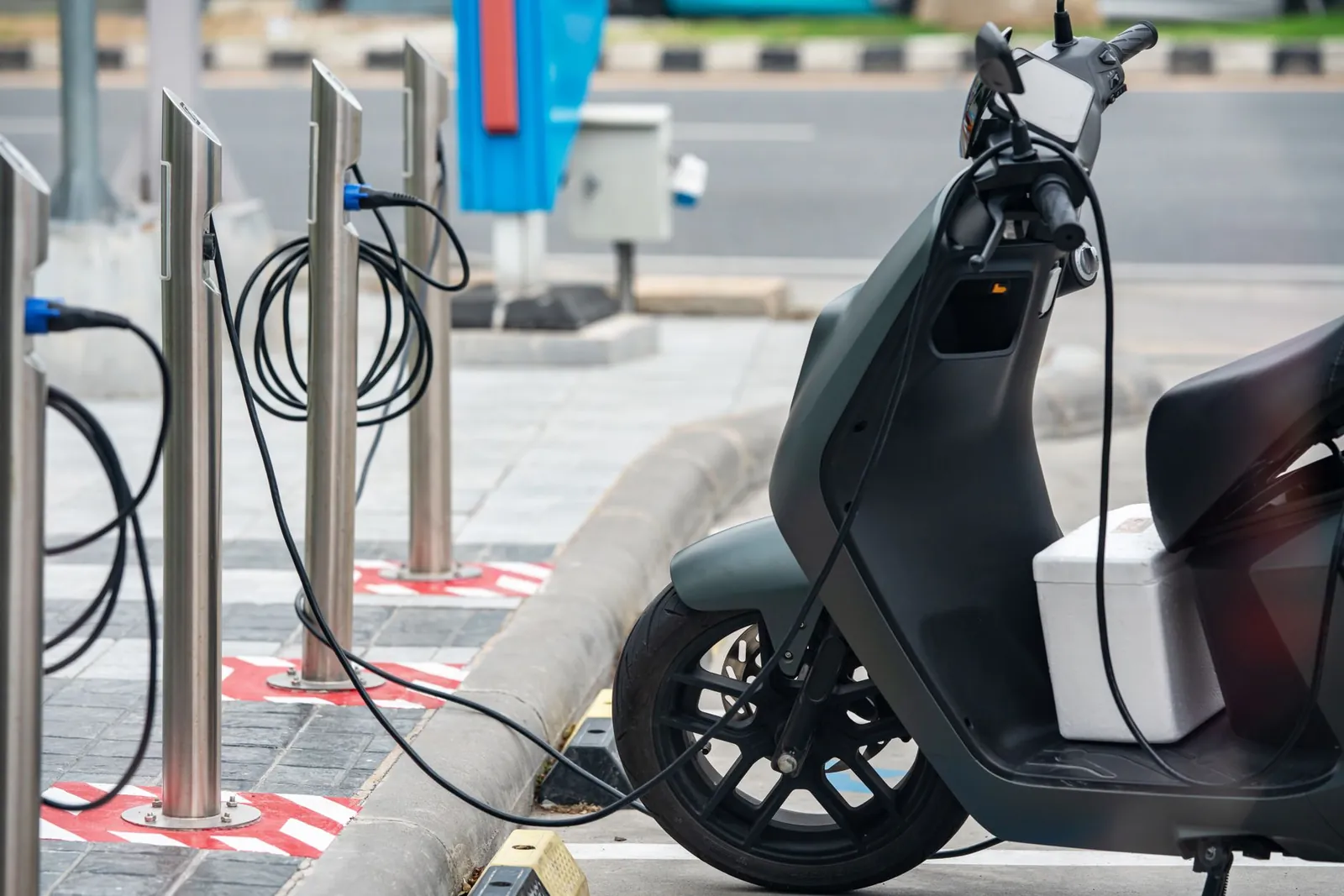 Electric scooter plugged into a charging station in a city environment, showcasing eco-friendly urban transportation. Stock photo illustrating Greaves Cotton's product launched story.