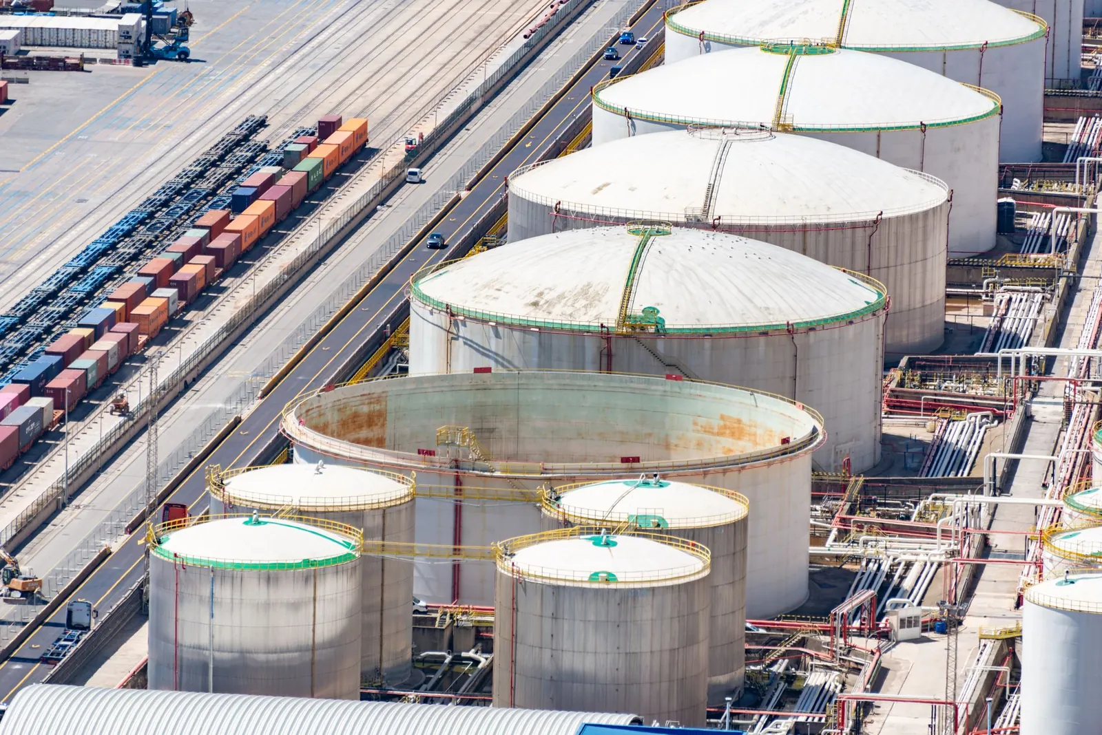 Aerial shot of large oil storage tanks in an industrial district with adjacent railway tracks. Stock photo illustrating Expo Engineering And Projects' new order story.
