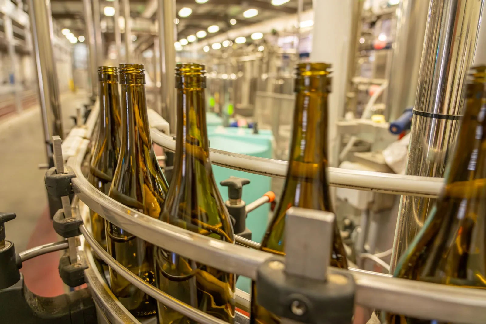 Close-up view of glass bottles on an industrial production line in a manufacturing facility. Stock photo illustrating Pyramid Technoplast's expansion story.