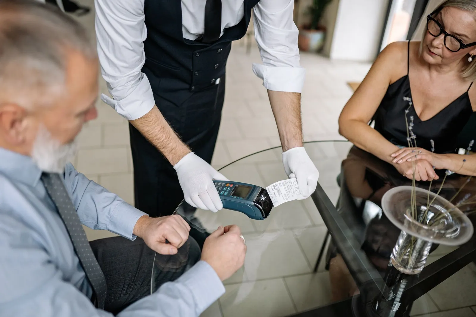 A couple making a contactless payment using a credit card at a restaurant table. Stock photo illustrating IndusInd Bank's product launched story.