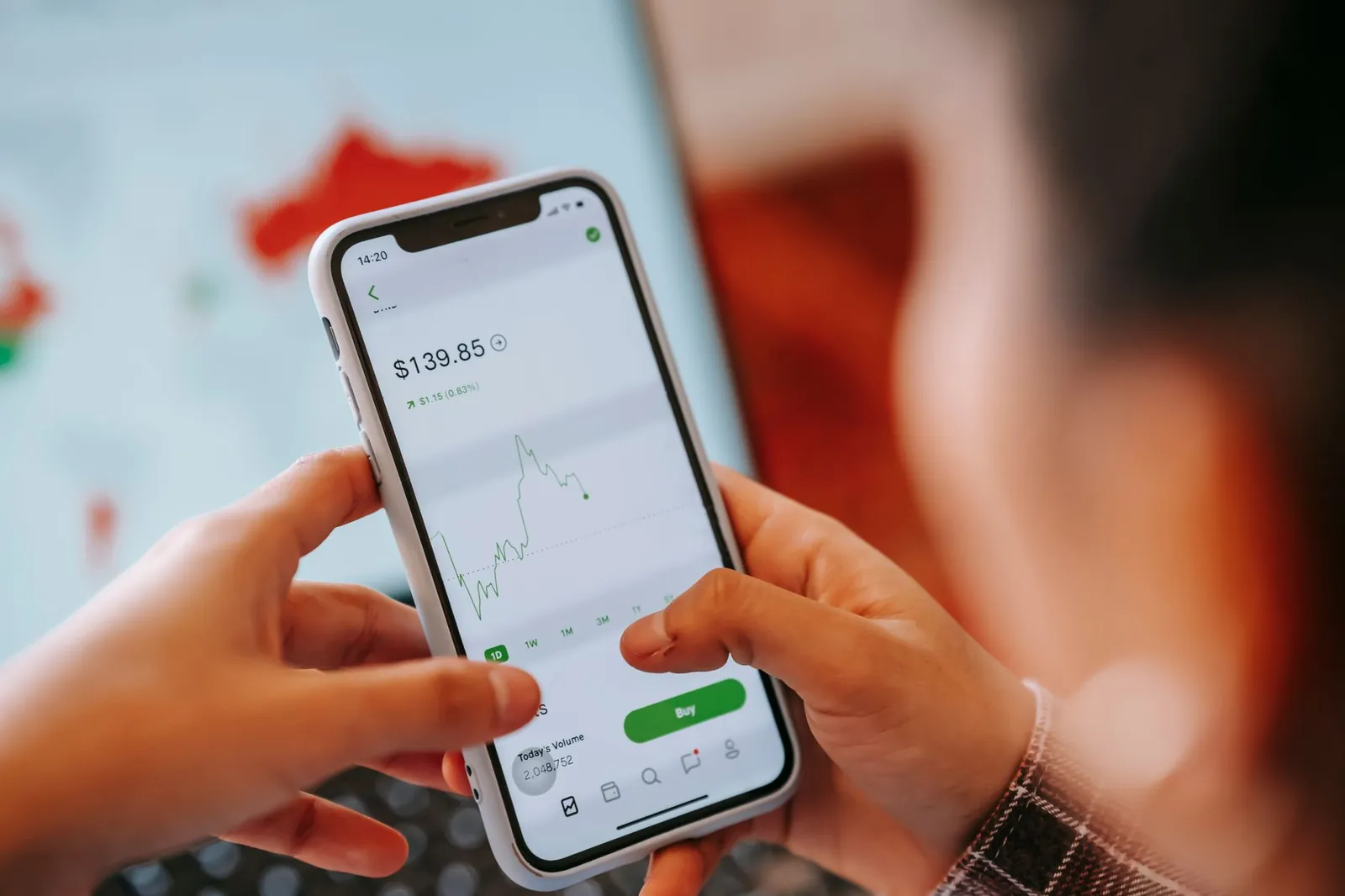 Crop anonymous trader using app on cellphone with graph and dollar price on screen in house. Stock photo illustrating Easy Trip Planners' product launched story.