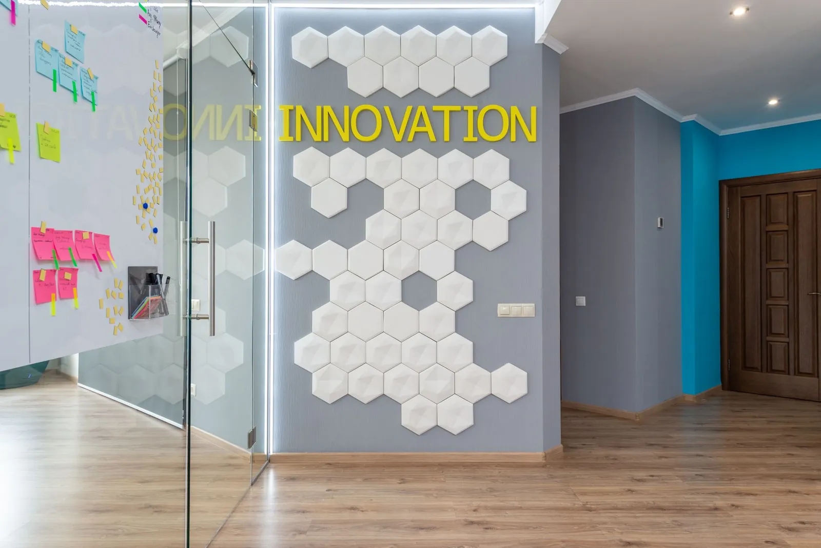 Geometric decoration on wall with Innovation inscription near glass door of conference room with colorful stickers in hallway of office building. Stock photo illustrating Adani Enterprises' fund raise story.