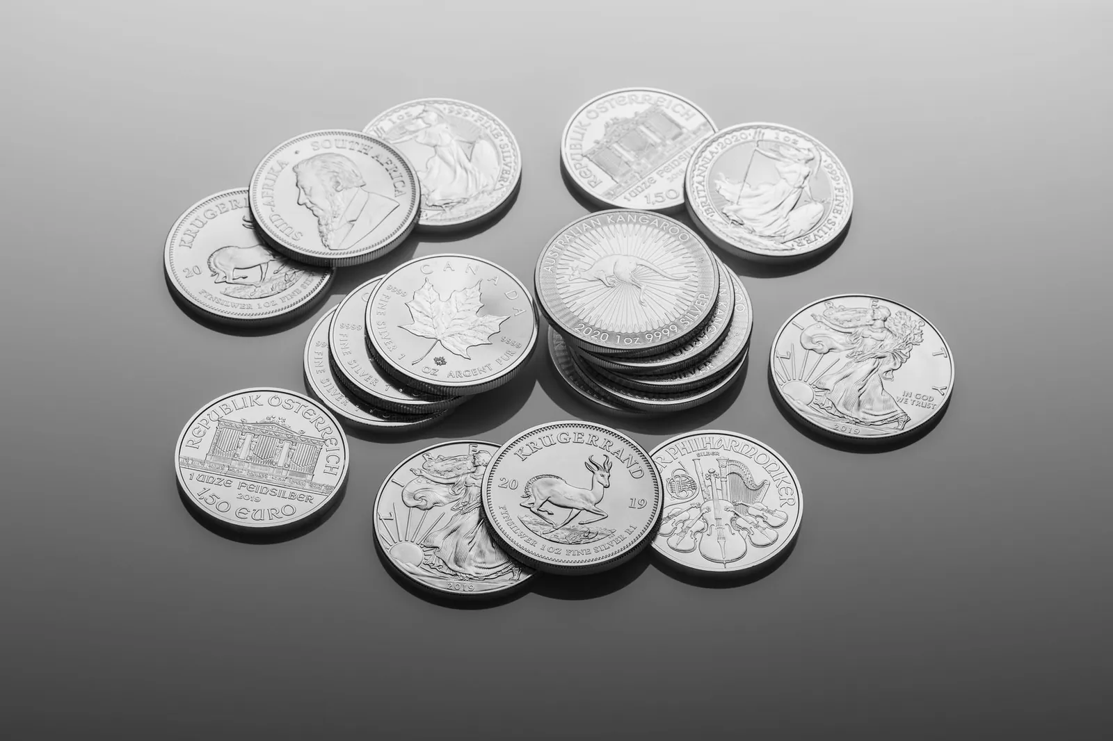 A close-up of various silver bullion coins, showcasing intricate designs on a reflective surface. Stock photo illustrating Multi Commodity Exchange of India's product launched story.
