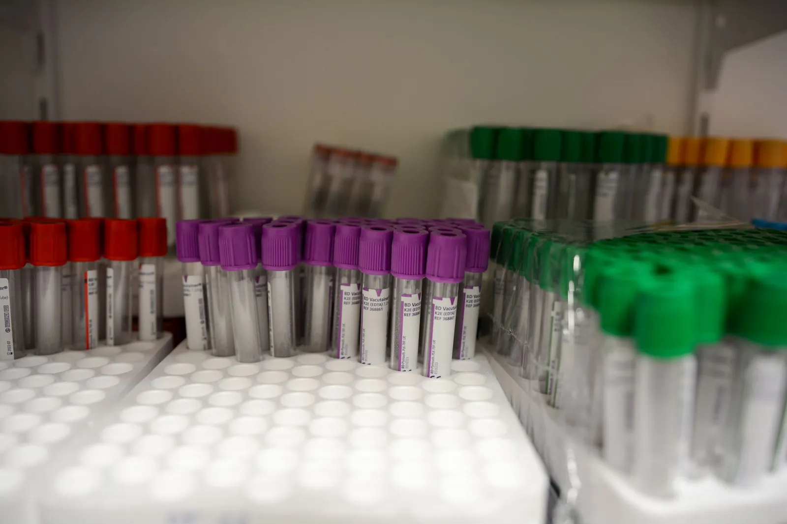Close-up of labeled blood collection tubes in a laboratory with red, purple, and green caps. Stock photo illustrating Hikal's regulatory approval story.