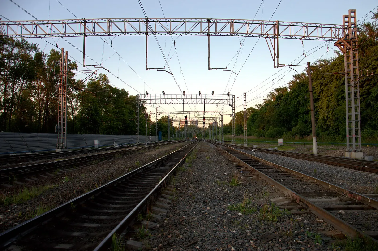 Scenic railway tracks at sunset with overhead electrical lines and greenery on the sides. Stock photo illustrating BCPL Railway Infrastructure's new order story.