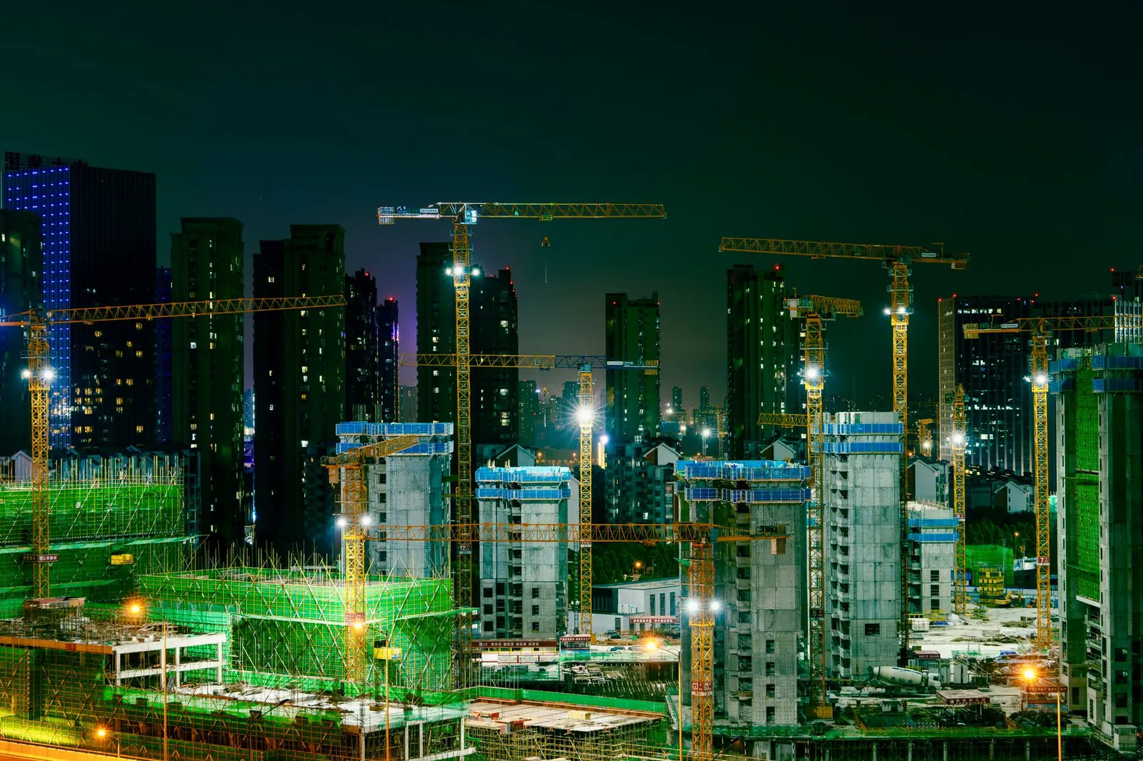 Night view of a bustling construction site in an urban cityscape with cranes and high-rise buildings. Stock photo illustrating Capacit'e Infraprojects' earning call story.
