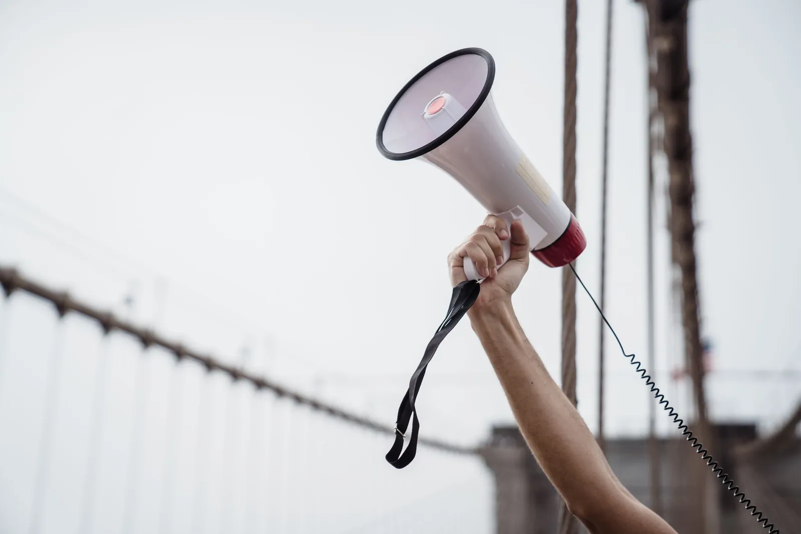 A hand holding a megaphone, symbolizing protest or announcement at an outdoor rally. Stock photo for the ALFA News guide: NSE Announcement Alerts: A Guide to SEBI Disclosures.