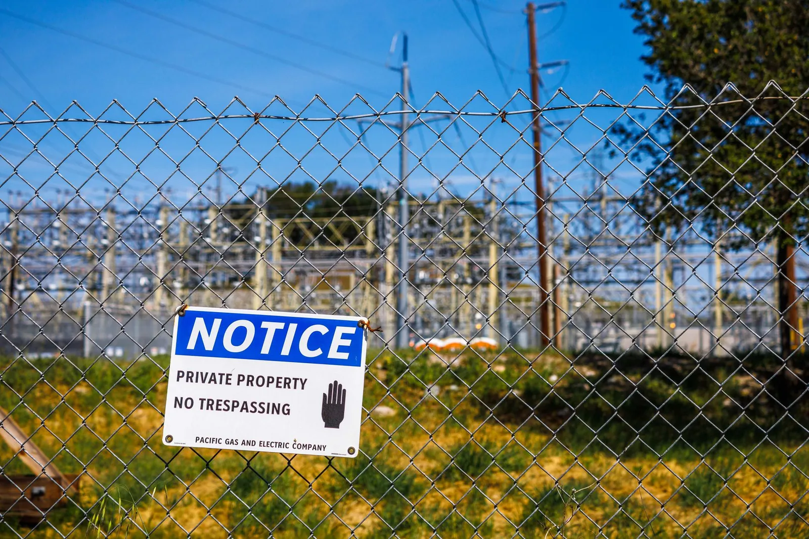 Chain link fence with a private property no trespassing notice sign and electrical infrastructure in the background. Stock photo illustrating SPML Infra's new order story.