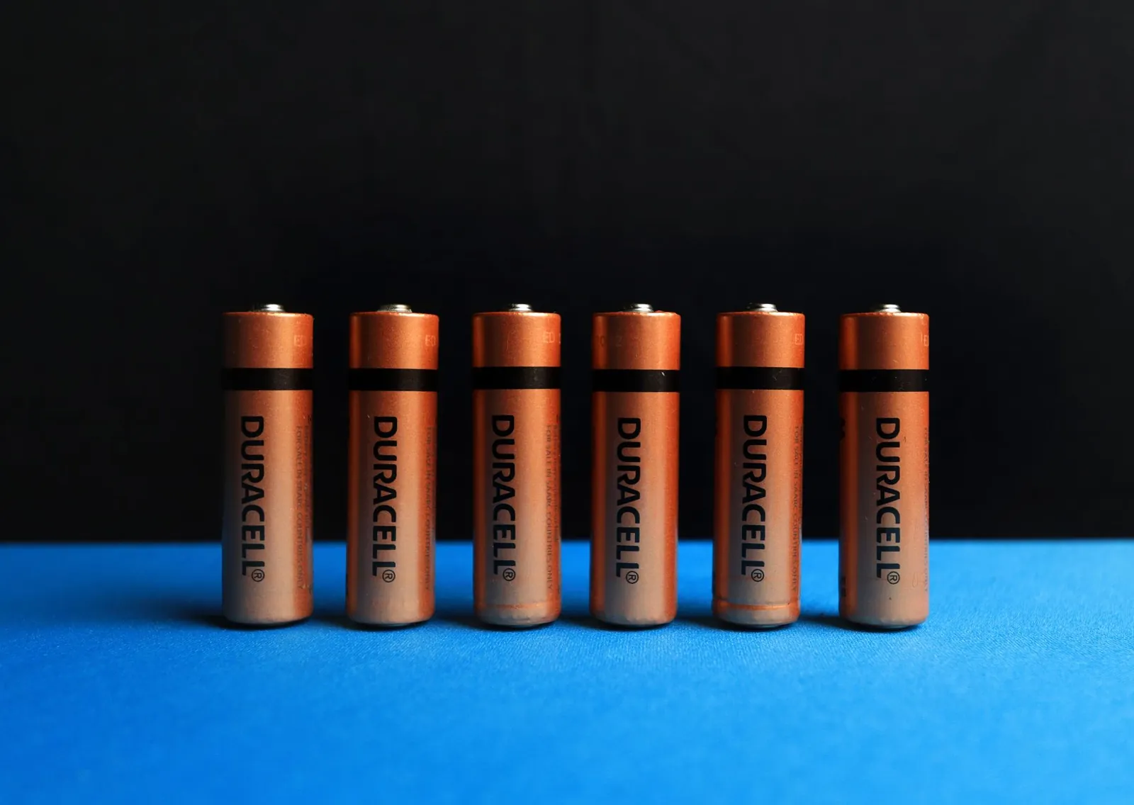 A lined up set of AA batteries with black and blue background. Stock photo illustrating Anupam Rasayan India's new order story.