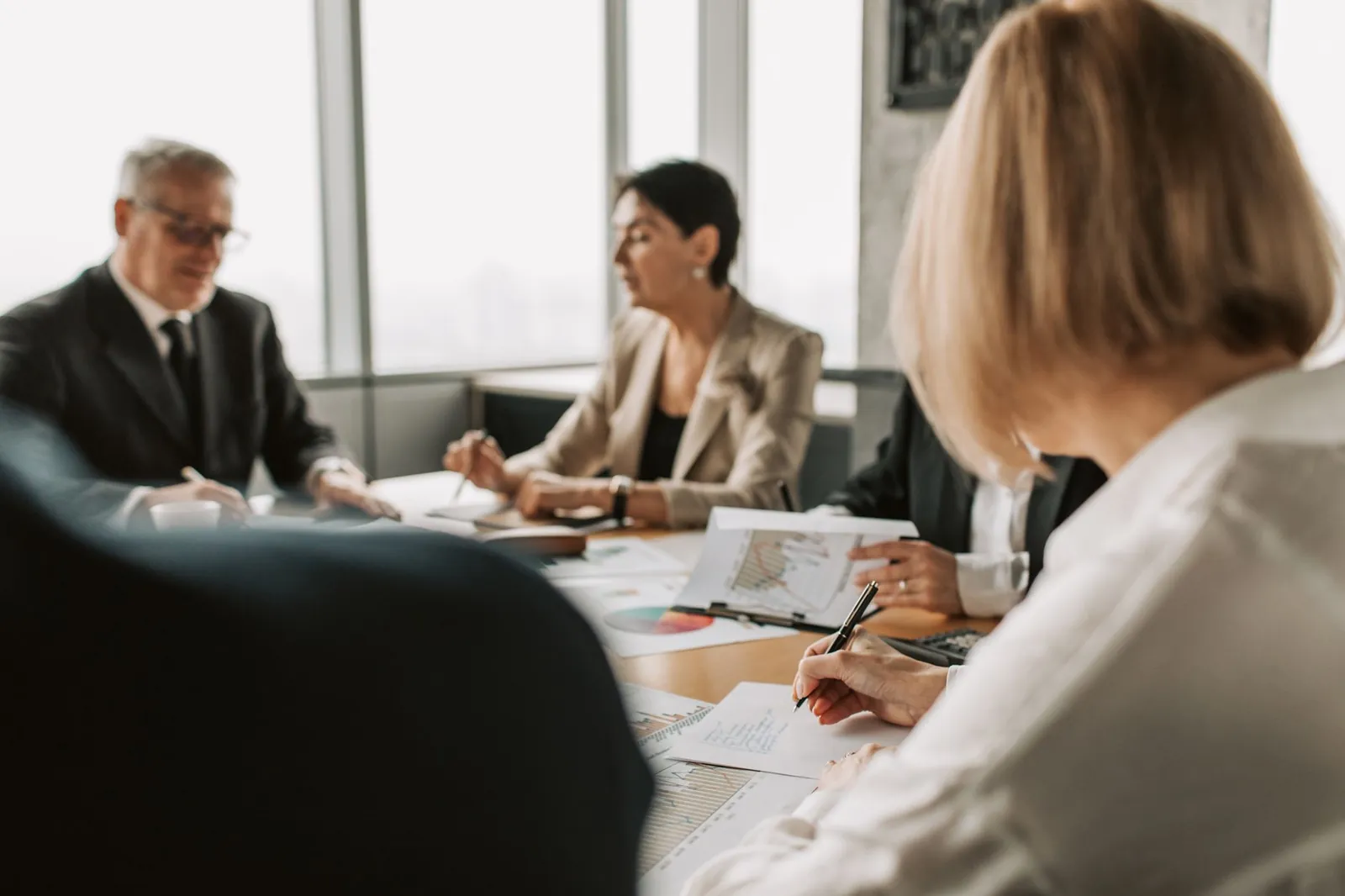 Colleagues discussing documents in a corporate office meeting. Stock photo for the ALFA News guide: How Fast Do Companies Have to Disclose? SEBI Timeline Guide.