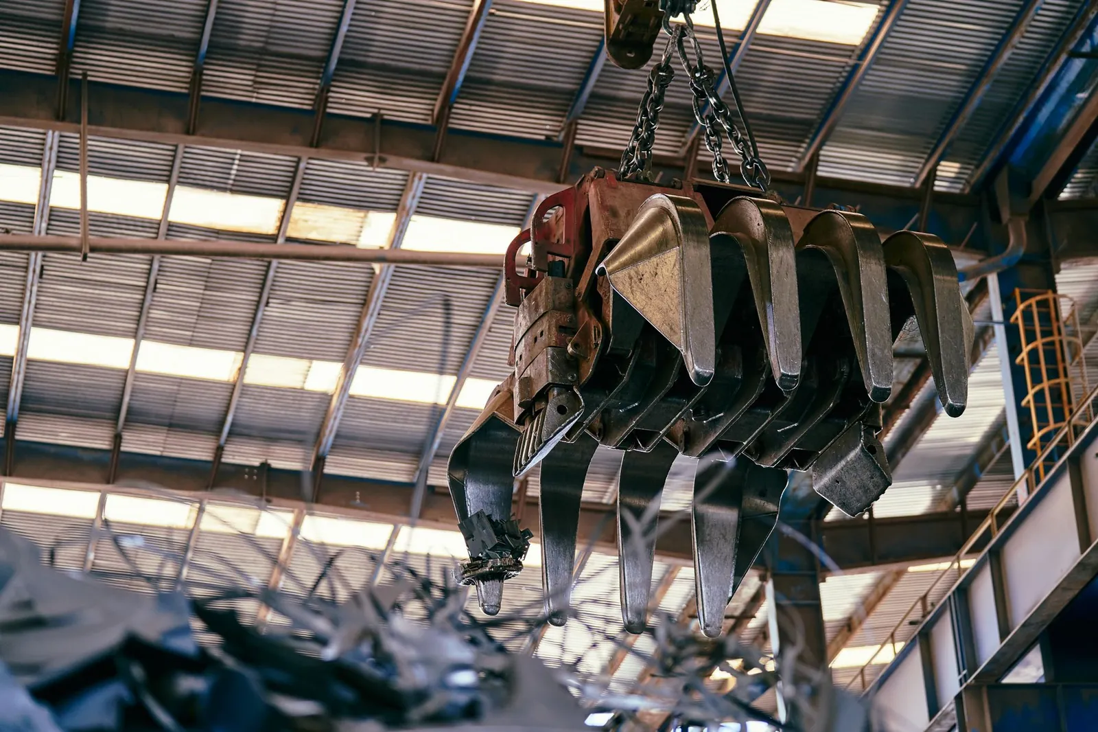 Large industrial crane handling scrap metal in a warehouse setting. Stock photo illustrating POCL Enterprises' earning call story.